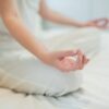 Woman doing meditation on bed in bedroom