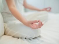 Woman doing meditation on bed in bedroom