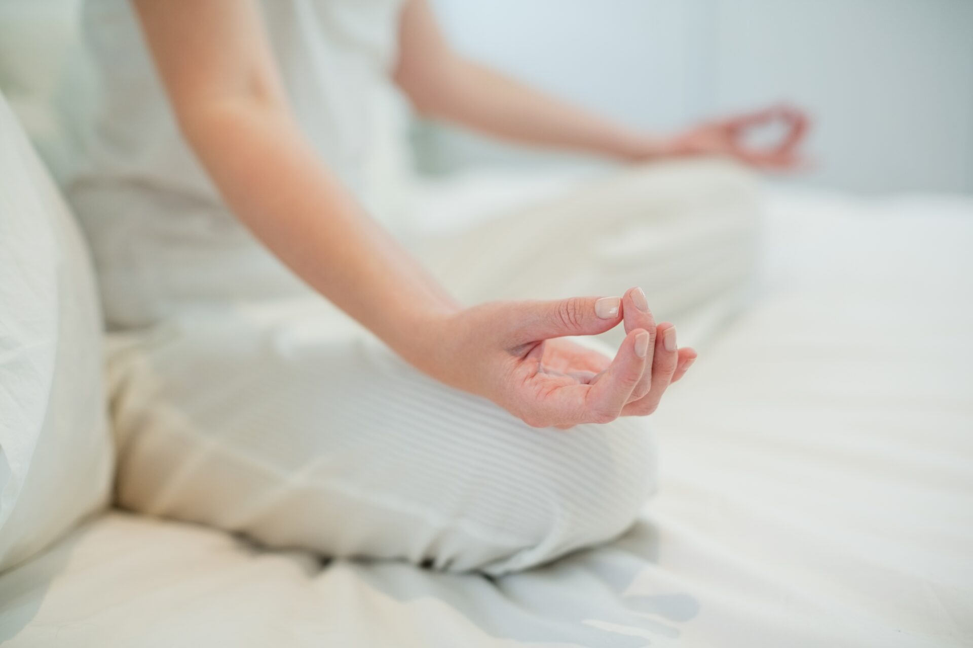 Woman doing meditation on bed in bedroom